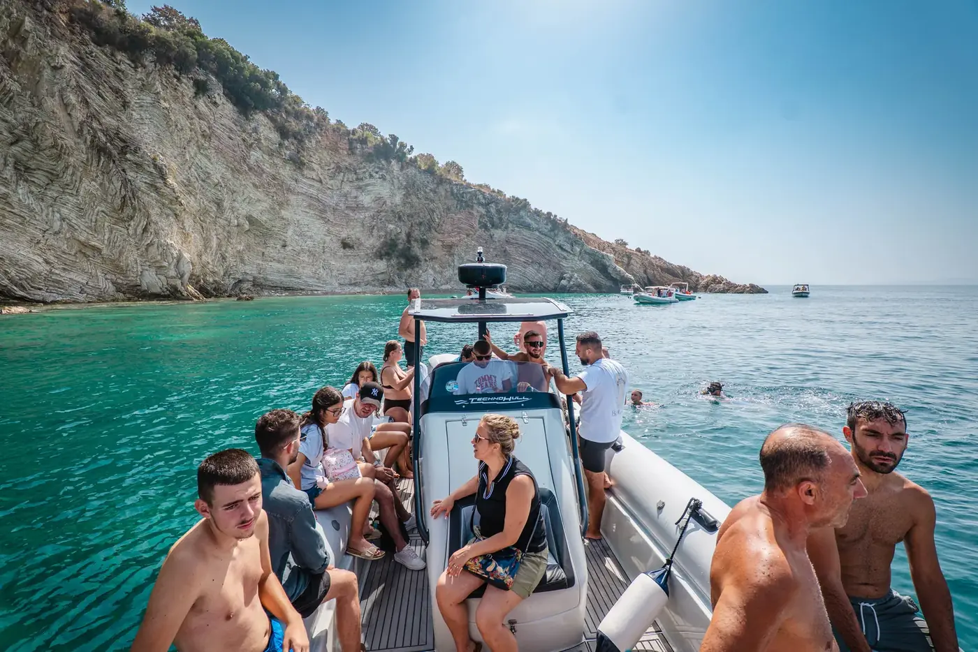 The Beast Boat's teak-effect deck and seating with white limestone cliffs rising behind